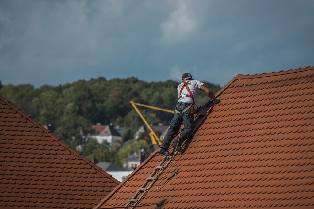 Couvreur encordé intervenant sur une toiture en tuiles