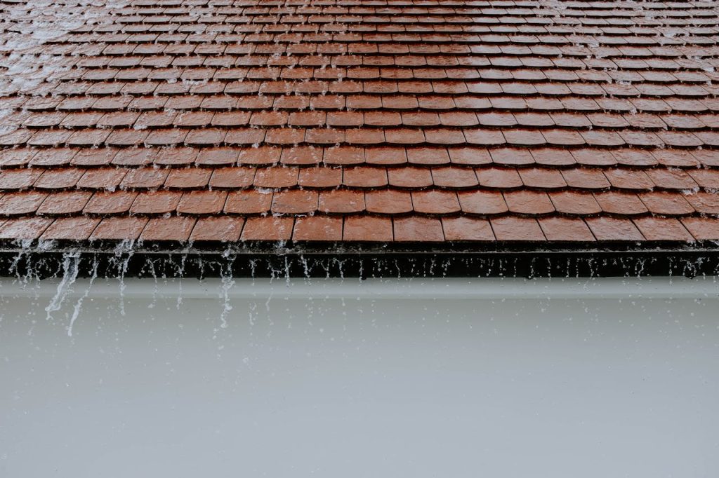 Pluie ruisselant sur une toiture en tuiles